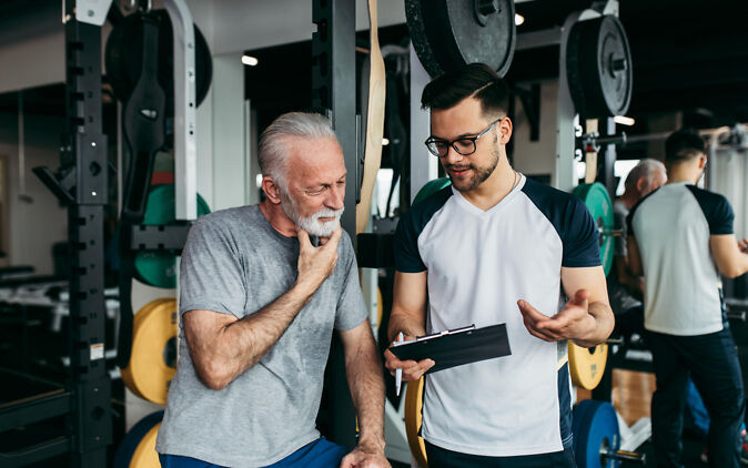 Fitnesstrainer erklärt Klient den Trainingsplan Fitnesstrainer erklärt Klient den Trainingsplan