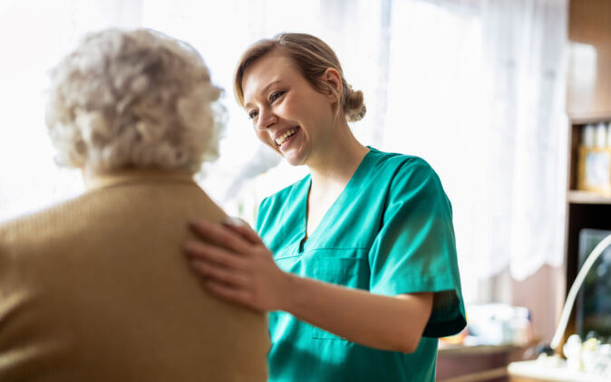 Pflegehelferin interagiert mit Seniorin