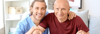 lächelnder Altenpfleger mit älterem Patienten