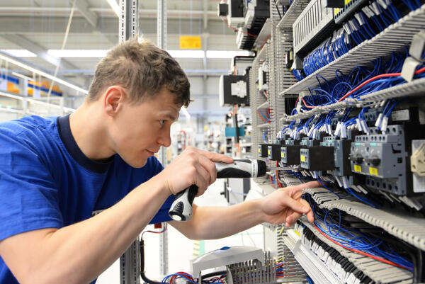 Elektroniker für Betriebstechnik befestigt Kabel