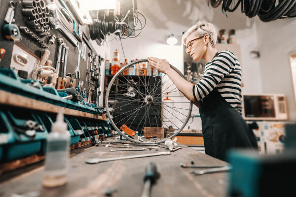 Zweiradmechatronikerin repariert Fahrrad