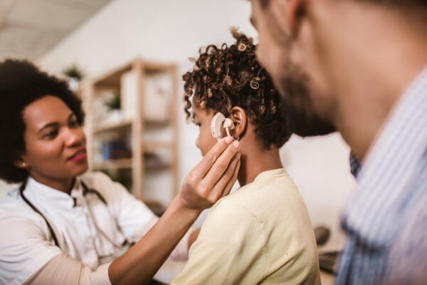 Ärztin überprüft Hörgerät eines jungen Kindes