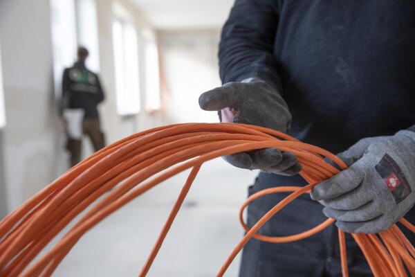 Elektroanlagenmonteur verlegt Kabel auf einer Baustelle