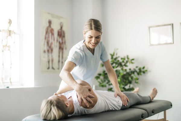 Physiotherapeutin führt Bewegungsübungen mit Patient durch
